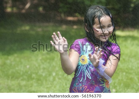 stock photo Cute Asian girl outside getting wet from sprinkler