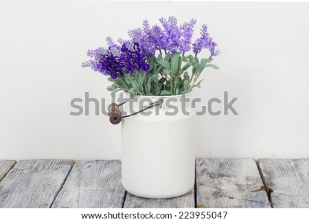 Bouquet of lilac spring flowers in a wooden blue vase on light shabby chic background