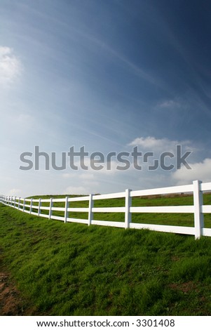 white country fence in green pasture in spring