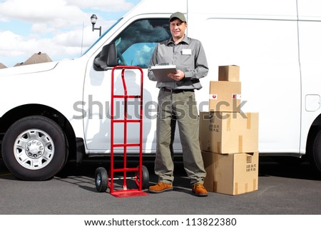 Smiling delivery courier standing near the white truck. Shipping service.