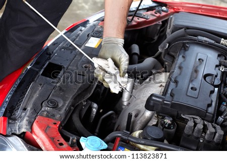 Auto mechanic checking oil. Car repair service.