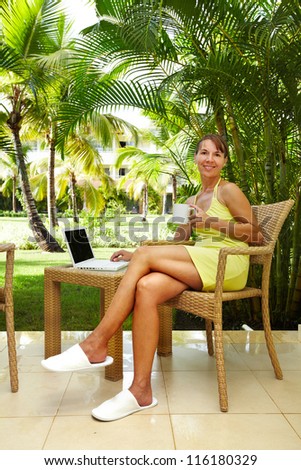 Woman with laptop computer in the tropical garden. Vacation.