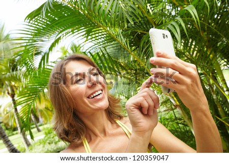 Woman with a smartphone in tropical garden. Vacation.