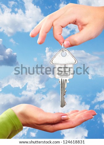 Hand with a home key. Over blue sky background.