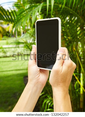 Woman with a smartphone in tropical garden. Vacation.