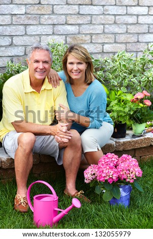 Happy senior couple with flowers in the garden.