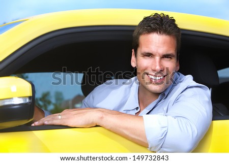 Happy young man driver in a new car.