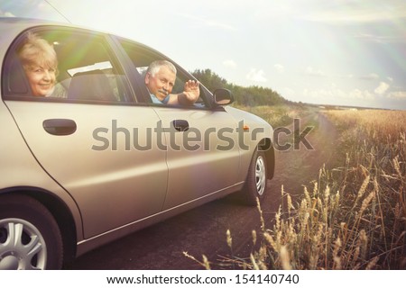 Two elderly people in car in field