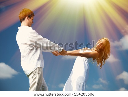 Happy dancing couple over blue sky background.