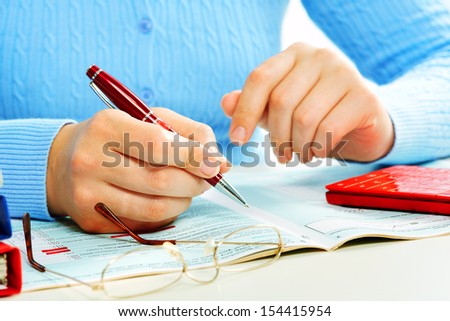 Hands of business woman filling tax form.