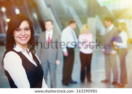 Young smiling pretty bussinesswoman over team background