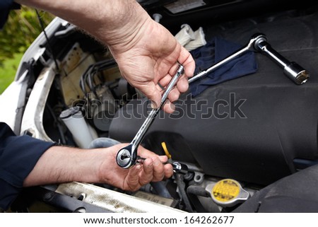 Hands of auto mechanic with wrench. Car repair service.