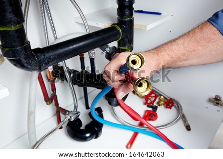 Hands of professional Plumber with a wrench. Clogged sink.