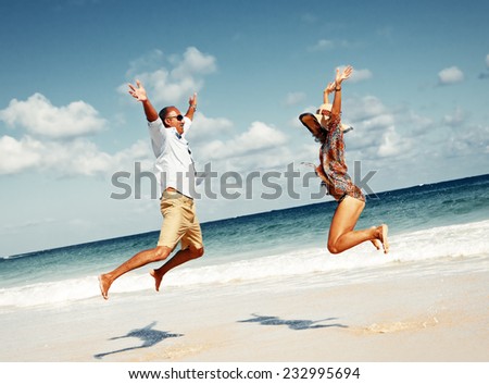 Happy couple jumping on the beach. Crazy vacation