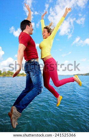 Happy man and woman jumping over water.