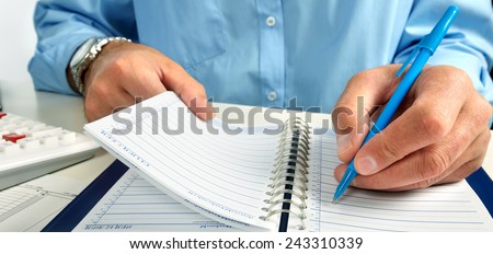Hand writing in notepad. Businessman working in office