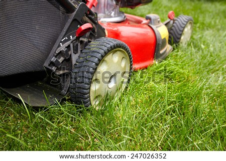 Red Lawn mower cutting grass. Gardening concept background