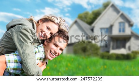 Happy couple near new home. Residential construction background.