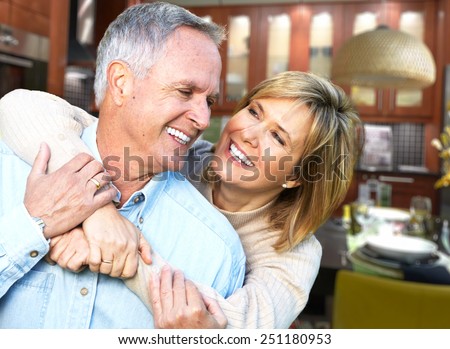 Happy senior loving couple over house background