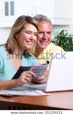 Senior couple looking bills at home with computer.