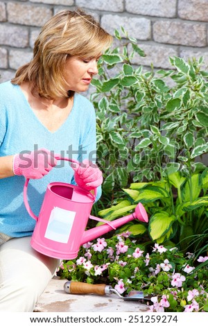 Happy senior woman gardening near new house.