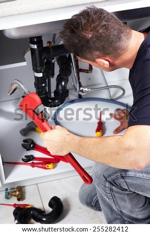Plumber man with tools in the kitchen. Plumbing and renovation.