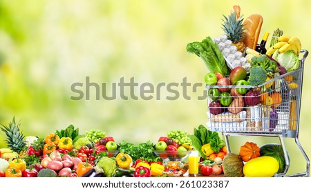 Shopping cart with vegetables over green background. Healthy diet.