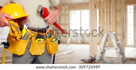 Builder handyman with construction tools. House renovation background.