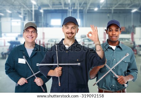 Smiling repairman with tire wrench in car repair service.