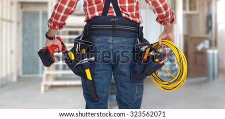 Electrician man with drill and wire cable over construction background.