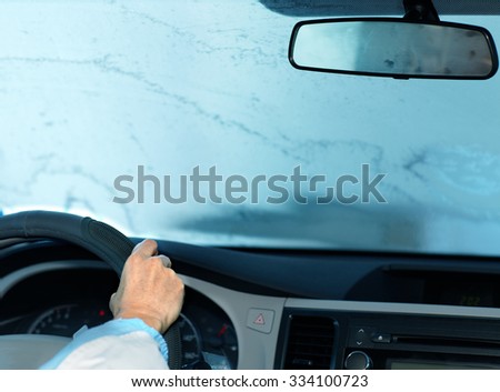 Woman driving with frozen windshield.  Driver insurance concept.