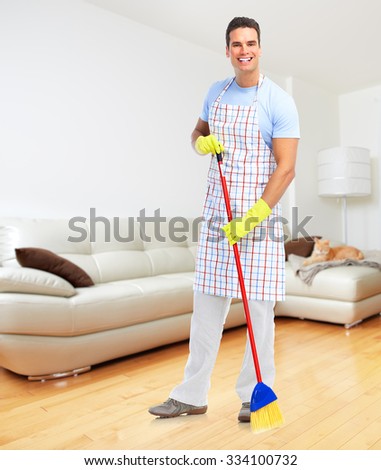 Smiling man cleaner with broom in modern apartment background