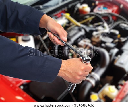 Hands of car mechanic with wrench in auto repair service.