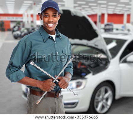 Smiling car mechanic with wrench in auto repair service.