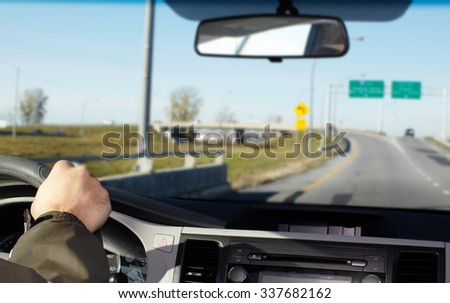 Hand of man driving on a highway. Driver insurance concept.