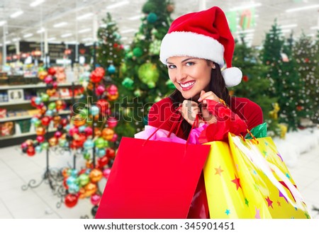Happy Santa Christmas woman with bags over X-mas Tree background.