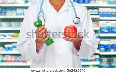 Doctor woman hands with dumbbell and apple over health care background.