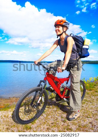 Young smiling  woman cycling near the lake