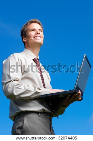 Happy successful  businessman with laptop   under blue sky.