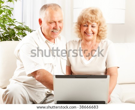 Happy smiling elderly couple working with laptop at home