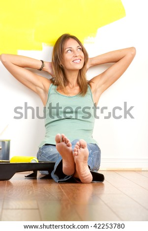 Renovation. Smiling beautiful woman painting interior wall of home.