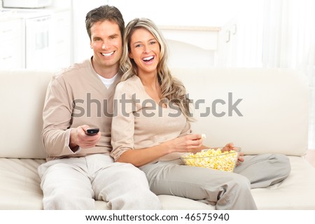 Young happy couple watching TV at home