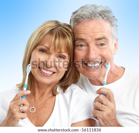 Happy seniors couple with toothbrushes. Healthy teeth. Over blue background
