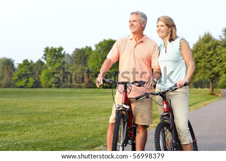 Happy elderly seniors couple biking in park