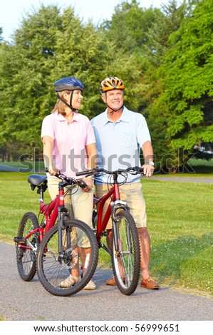 Happy elderly seniors couple biking in park