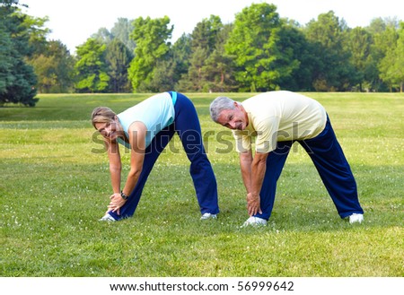 Happy elderly seniors couple working out in park