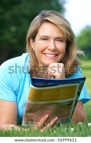 Happy smiling elderly woman reading a magazine