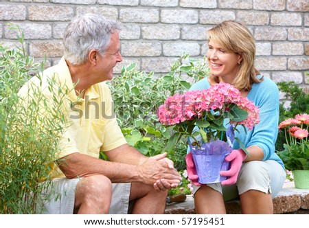 Smiling happy elderly seniors couple gardening near the home