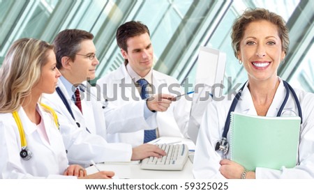 Smiling medical doctors with stethoscopes working with computer.