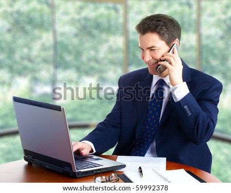 Handsome smiling businessman working with laptop.